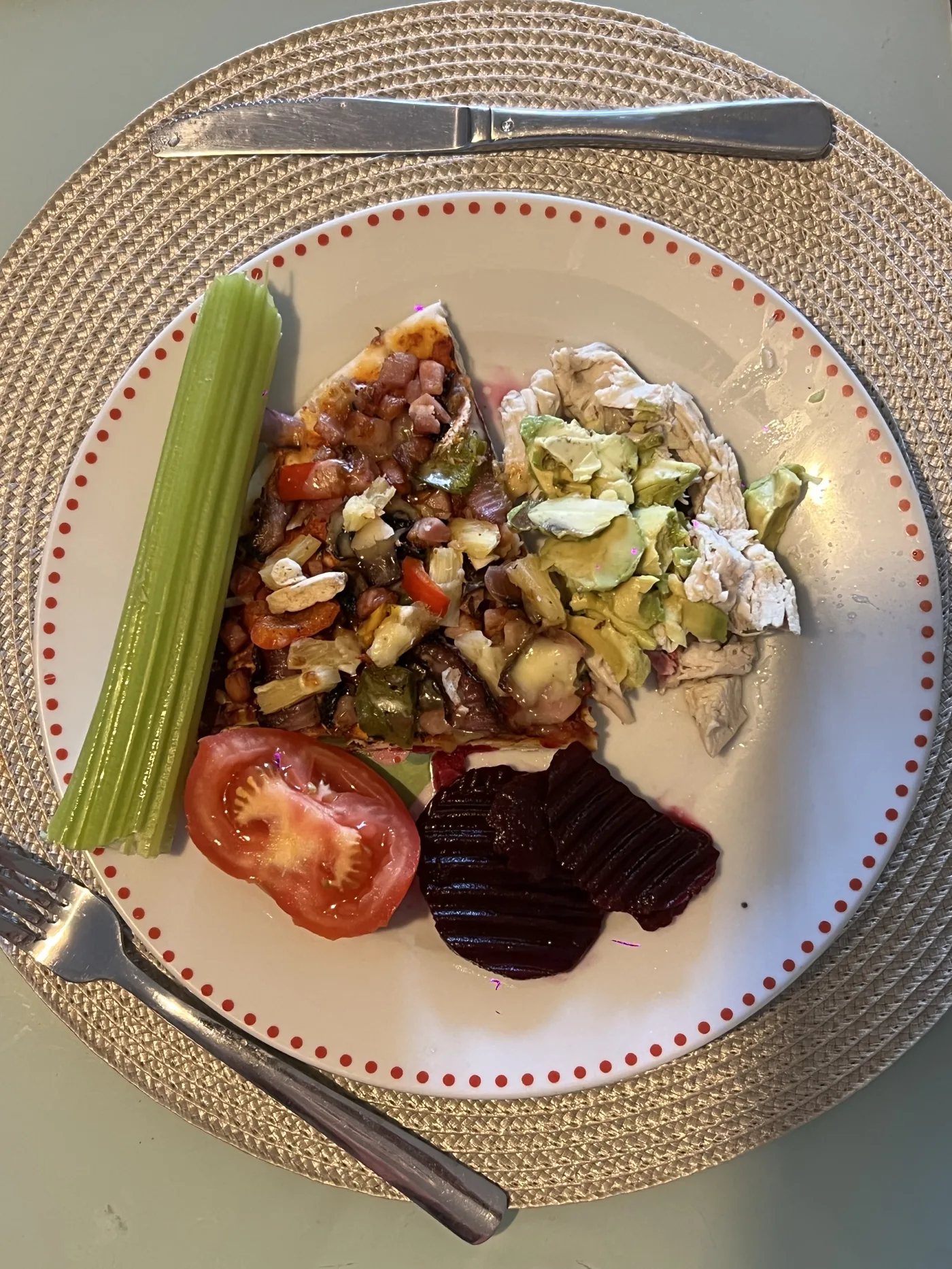Plate with pizza slice, chicken, avocado, tomato, celery and beetroot